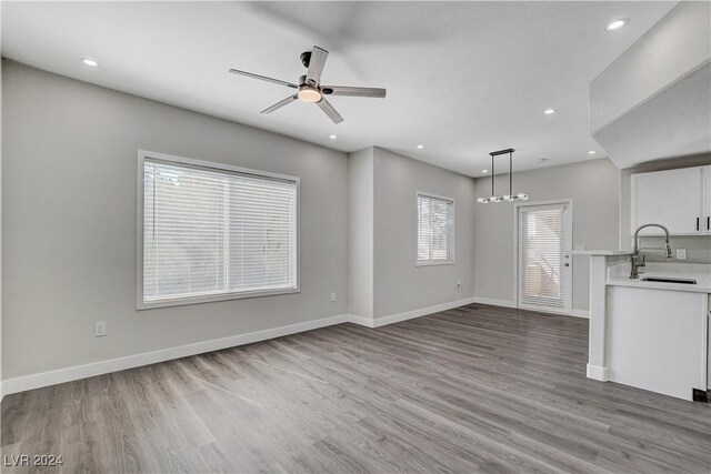 unfurnished living room with sink, light hardwood / wood-style flooring, and ceiling fan