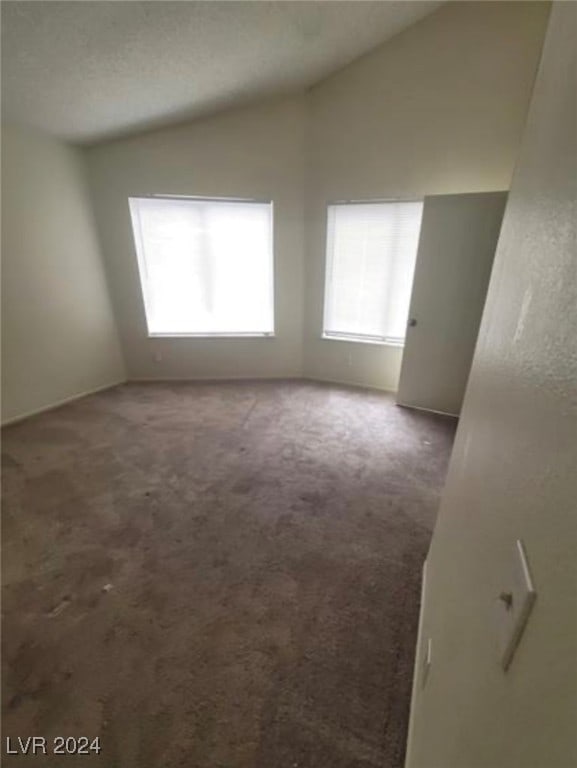 empty room with vaulted ceiling and carpet