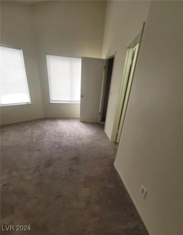 carpeted spare room with a towering ceiling