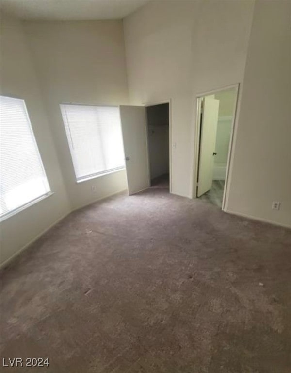 unfurnished bedroom featuring carpet floors, a high ceiling, and ensuite bath