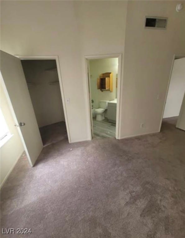 unfurnished bedroom with carpet, a closet, ensuite bath, and a walk in closet