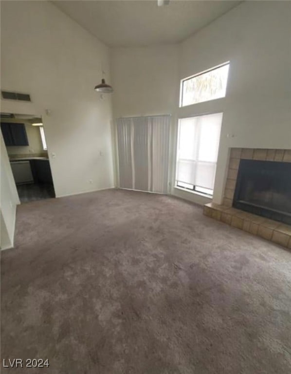 unfurnished living room with a fireplace, carpet, and a towering ceiling