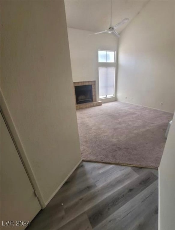 unfurnished living room featuring ceiling fan, carpet flooring, lofted ceiling, and a tiled fireplace