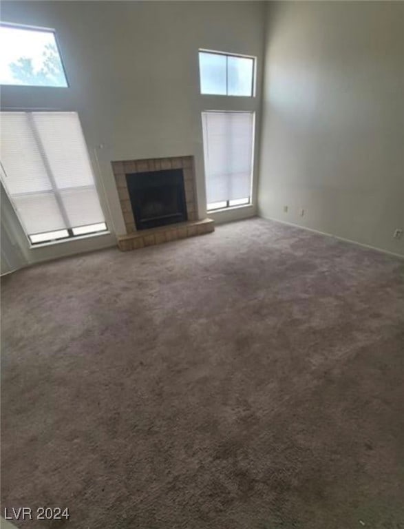 unfurnished living room featuring a wealth of natural light, a fireplace, and carpet flooring