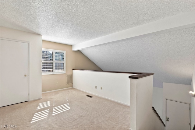 additional living space featuring light carpet, a textured ceiling, and vaulted ceiling with beams