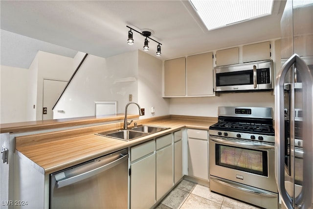 kitchen featuring sink, light tile patterned floors, appliances with stainless steel finishes, and cream cabinetry