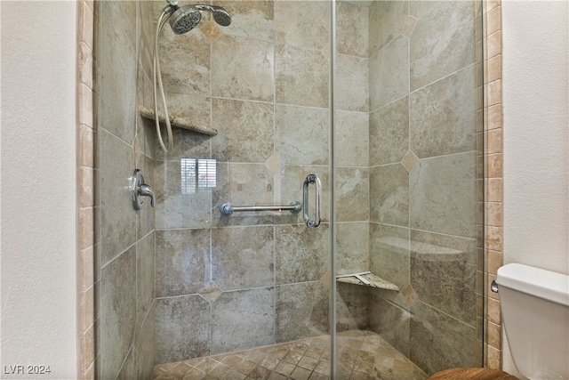 bathroom featuring a shower with door and toilet