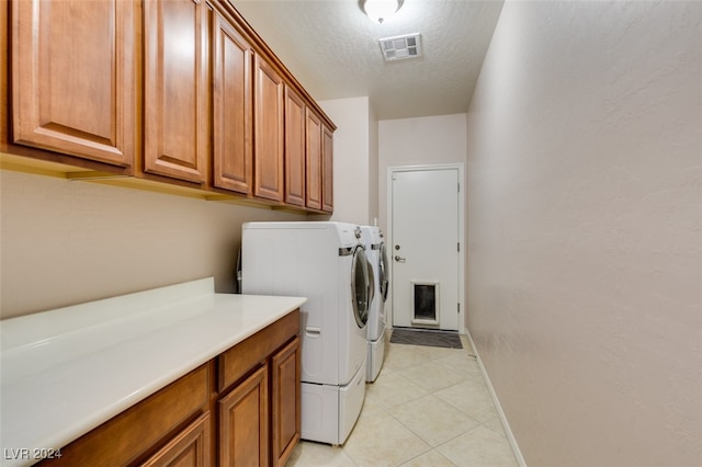 clothes washing area featuring separate washer and dryer, light tile patterned flooring, a textured ceiling, and cabinets