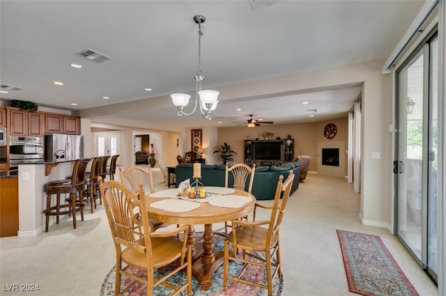 dining room featuring light tile patterned floors and ceiling fan with notable chandelier