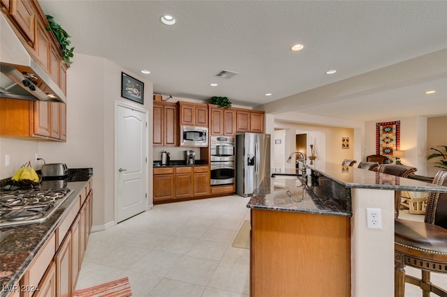 kitchen featuring appliances with stainless steel finishes, a center island with sink, light tile patterned floors, and sink