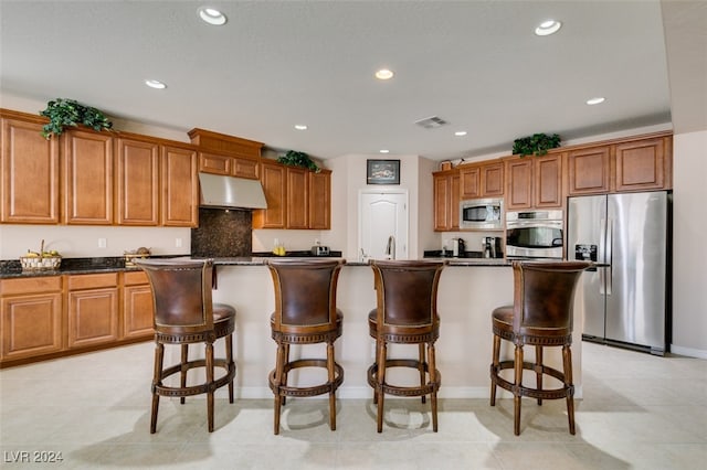 kitchen with appliances with stainless steel finishes, a kitchen island, light tile patterned floors, and dark stone counters