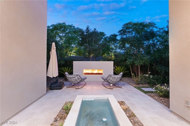 patio terrace at dusk featuring a hot tub