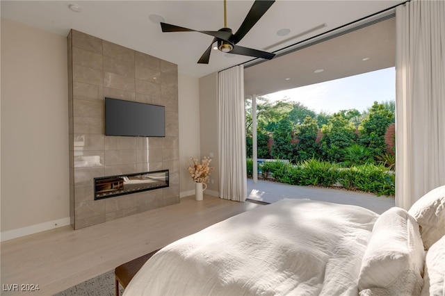 bedroom with ceiling fan, access to outside, tile walls, hardwood / wood-style flooring, and a fireplace