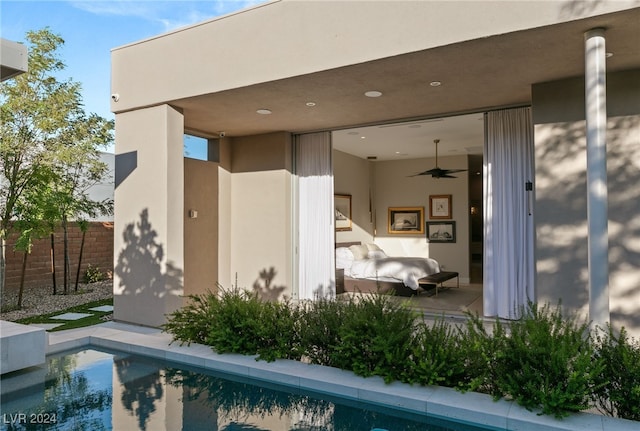 back of property with ceiling fan and a fenced in pool