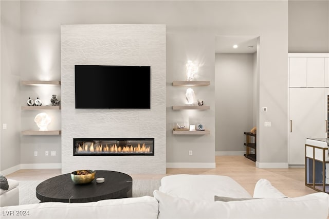 living room featuring a fireplace, built in shelves, and light wood-type flooring