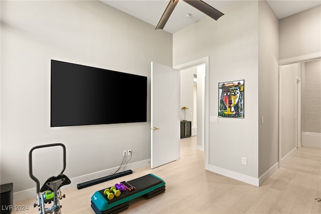 exercise room with a high ceiling and light wood-type flooring