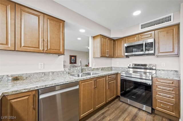 3111 Bel Air Dr Unit 8A, Las Vegas, NV 89109 - kitchen featuring stainless steel appliances, a sink, dark wood-style flooring, brown cabinets, and light stone counters