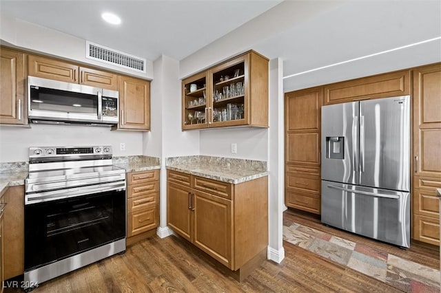 3111 Bel Air Dr Unit 8A, Las Vegas, NV 89109 - kitchen featuring stainless steel appliances, dark wood-type flooring, glass insert cabinets, brown cabinetry, and recessed lighting