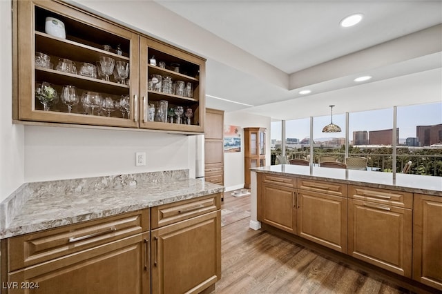 kitchen with pendant lighting, light wood-type flooring, and light stone counters