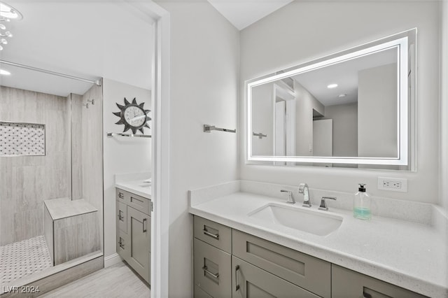 bathroom with vanity, wood-type flooring, and tiled shower