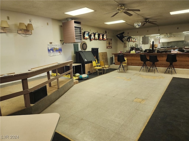 interior space with a textured ceiling, ceiling fan, light tile patterned floors, and a workshop area