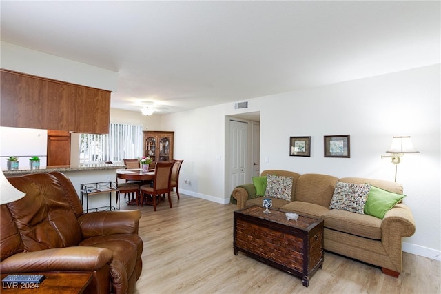 living room featuring light wood-type flooring, visible vents, and baseboards