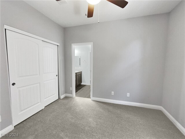 unfurnished bedroom with ceiling fan, a closet, carpet, and ensuite bath