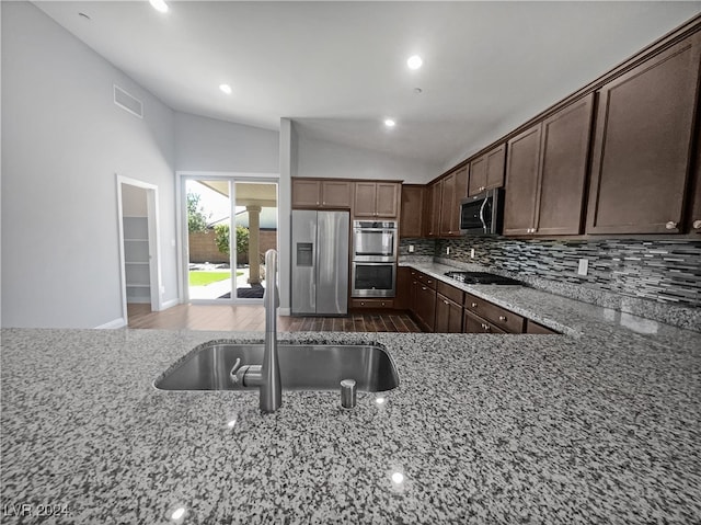 kitchen featuring appliances with stainless steel finishes, backsplash, dark hardwood / wood-style floors, sink, and light stone counters