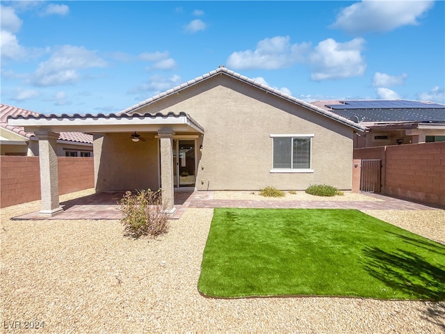 rear view of property with a patio area, a yard, and solar panels