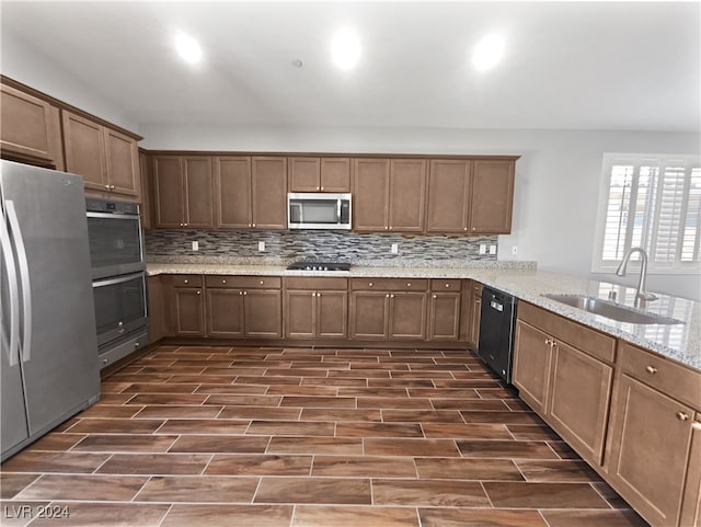 kitchen with tasteful backsplash, sink, light stone counters, black appliances, and kitchen peninsula