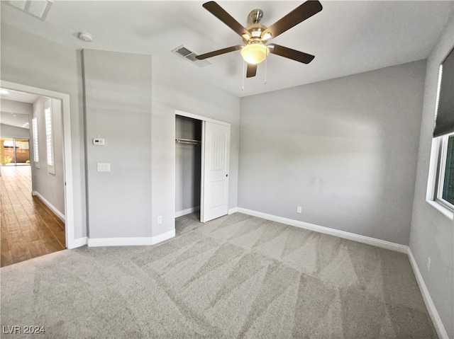 unfurnished bedroom featuring light colored carpet, a closet, and ceiling fan