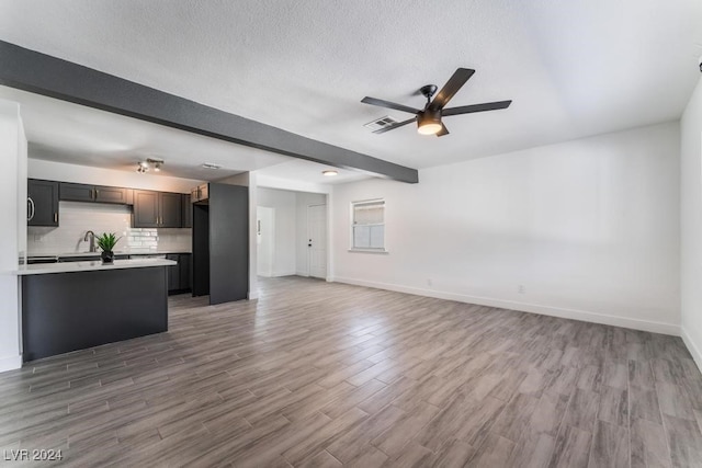 unfurnished living room with ceiling fan, dark hardwood / wood-style flooring, a textured ceiling, and beam ceiling