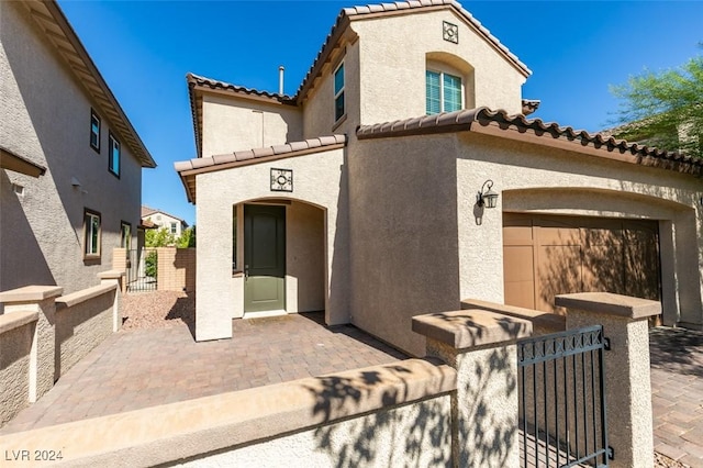 mediterranean / spanish house with a fenced front yard, a tile roof, and stucco siding