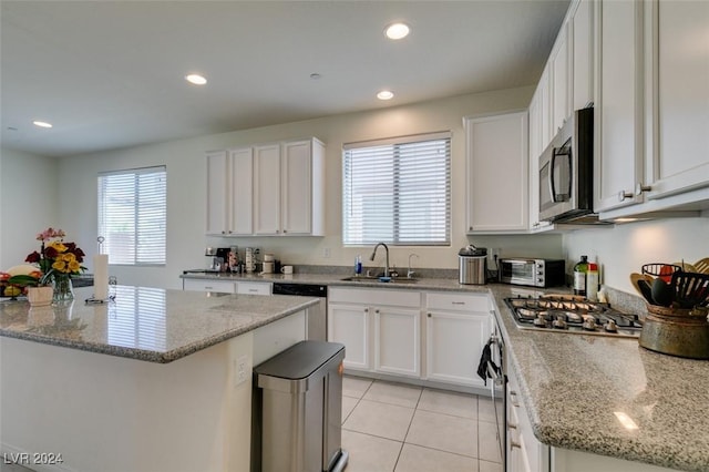 kitchen featuring sink, white cabinetry, stainless steel appliances, light stone countertops, and a kitchen island