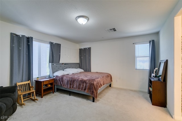 bedroom with light carpet, baseboards, multiple windows, and visible vents