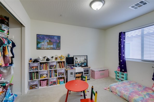 rec room with carpet floors, visible vents, and a textured ceiling