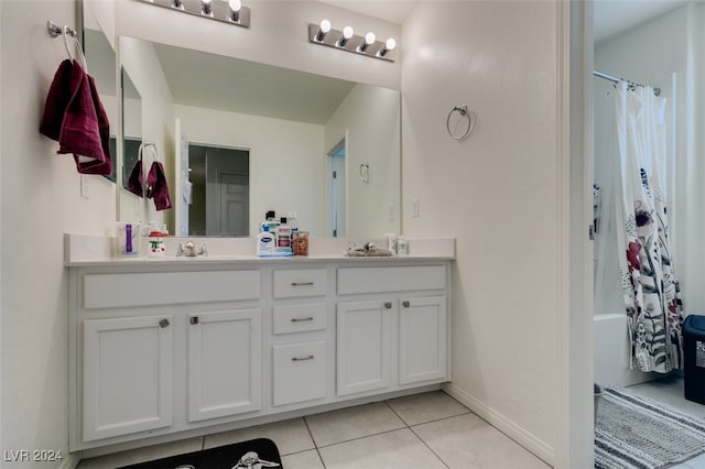 full bath featuring double vanity, shower / bath combo with shower curtain, a sink, tile patterned flooring, and baseboards