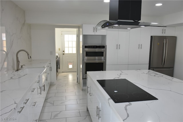 kitchen featuring light stone counters, stainless steel appliances, island range hood, sink, and white cabinetry