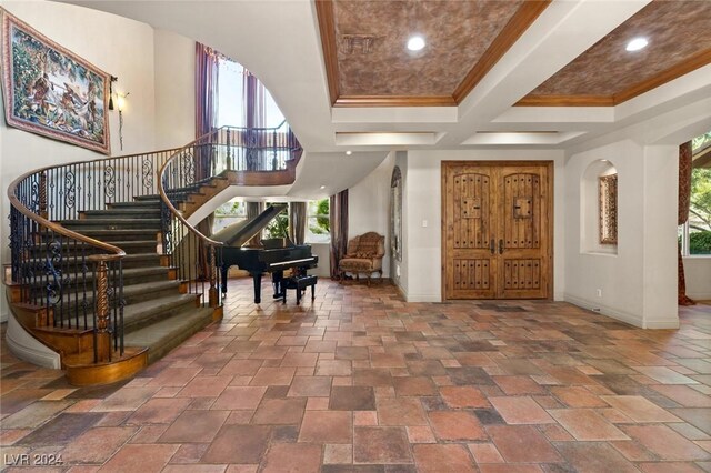 tiled entryway with coffered ceiling, a high ceiling, and ornamental molding