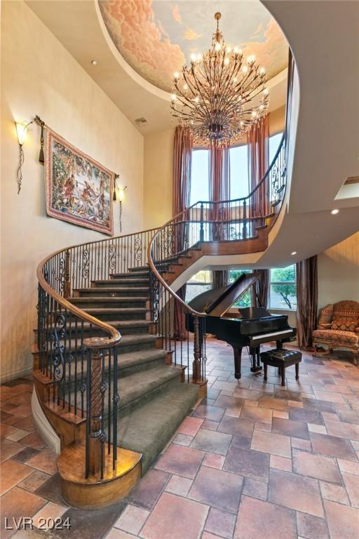 staircase with tile patterned floors, a tray ceiling, a high ceiling, and a chandelier