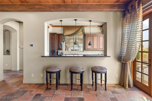 kitchen with a breakfast bar area, decorative light fixtures, kitchen peninsula, and dark tile patterned flooring