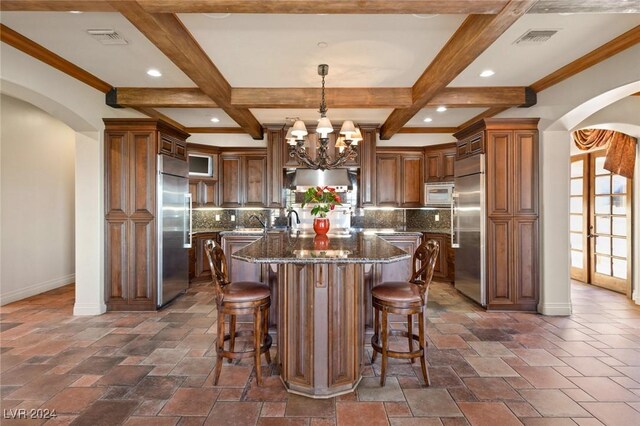 kitchen featuring a large island, decorative backsplash, built in refrigerator, and coffered ceiling