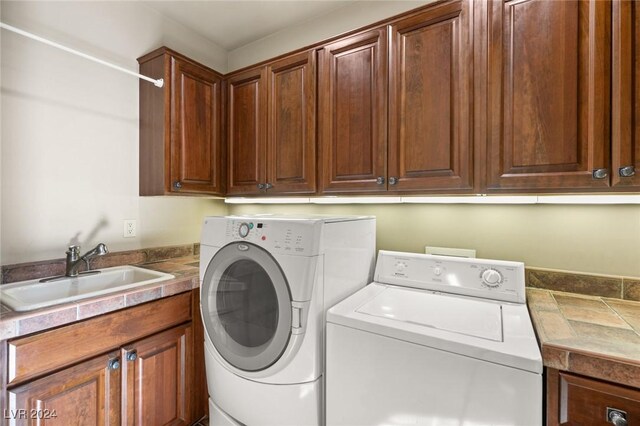 washroom featuring sink, washing machine and clothes dryer, and cabinets