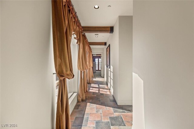 hallway with tile patterned floors and beam ceiling