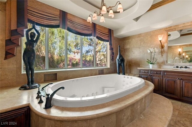 bathroom featuring a wealth of natural light, a raised ceiling, vanity, and tiled bath