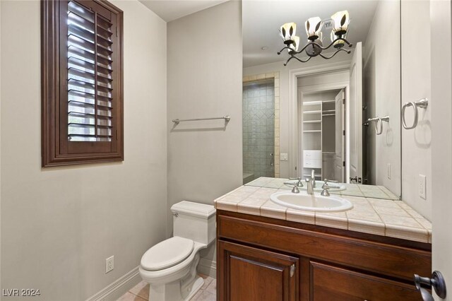 bathroom featuring tile patterned floors, vanity, a chandelier, and toilet