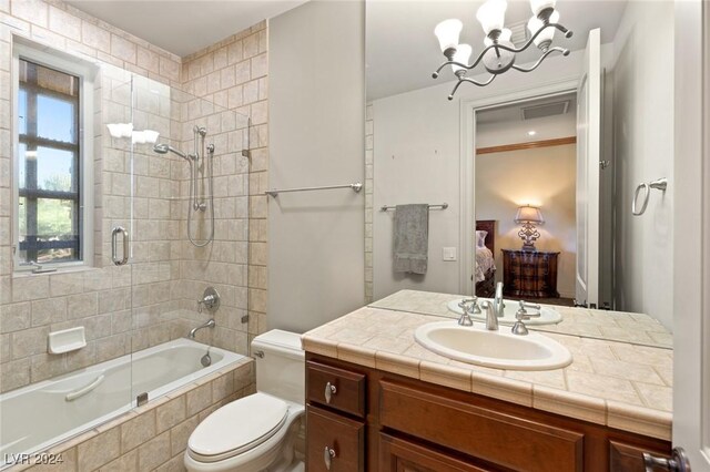 full bathroom with vanity, shower / bath combination with glass door, a chandelier, and toilet