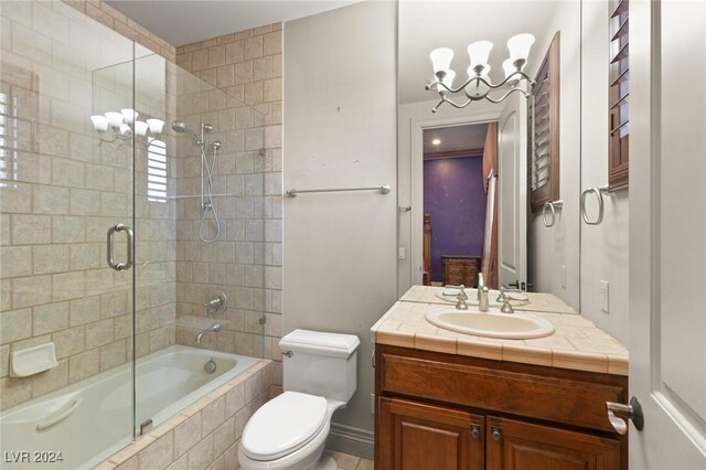 full bathroom featuring combined bath / shower with glass door, a notable chandelier, vanity, and toilet