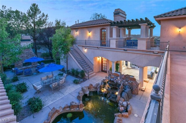 back house at dusk with a balcony and a patio area