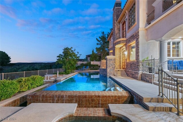 pool at dusk featuring a patio area